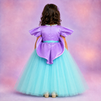 Child wearing a purple and turquoise dress with a colorful background