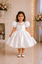 Young girl in a white dress standing in a decorated room with flowers and lights.